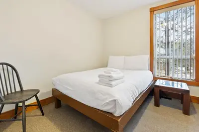 a bedroom with a bed with a chair and a window at 3 Level Ski Chalet 7BR w Deck, Sauna & Ping-Pong! in Blue Mountains