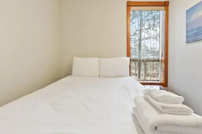 a white bed in a room with a window at 3 Level Ski Chalet 7BR w Deck, Sauna & Ping-Pong! in Blue Mountains