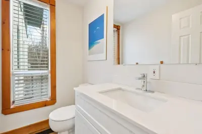 a white bathroom with a sink and a toilet at 3 Level Ski Chalet 7BR w Deck, Sauna & Ping-Pong! in Blue Mountains