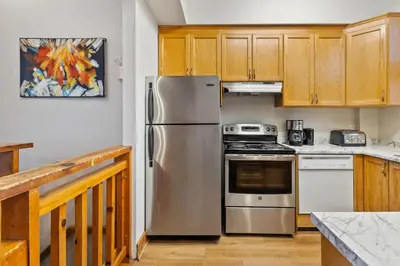 a kitchen with stainless steel appliances and wooden cabinets at 3 Level Ski Chalet 7BR w Deck, Sauna & Ping-Pong! in Blue Mountains