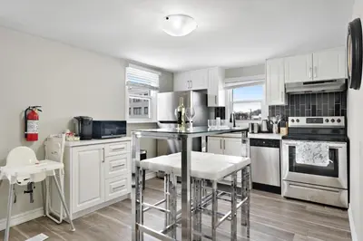 a kitchen with white cabinets and a table and chairs at Separate 3BR Family Friendly Apartments, Separate Floors, 5 Minutes Walk to The Fallsview with Free Parking & Wine in Niagara Falls