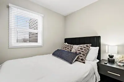 a white bedroom with a bed and a window at Separate 3BR Family Friendly Apartments, Separate Floors, 5 Minutes Walk to The Fallsview with Free Parking & Wine in Niagara Falls