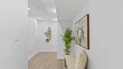 a white hallway with a chair and a plant at Family Friendly - HOT TUB - Near Toronto & UOIT in Oshawa