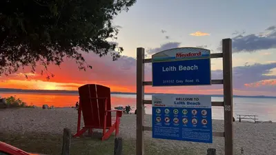 a sign on a beach with a chair and a sunset at Casa Maria Irena in Meaford