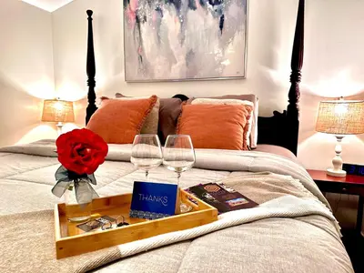 a bed with a tray with wine glasses and a rose at Settlers Suites in Niagara on the Lake