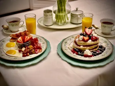 a table with two plates of pancakes and fruit at Settlers Suites in Niagara on the Lake