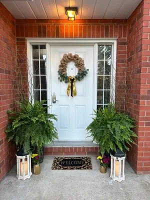 a white front door with a wreath and two potted plants at Settlers Suites in Niagara on the Lake