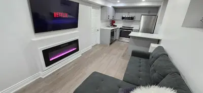 a living room with a couch and a tv on a wall at Cozy 2 Bedrooms & 2 Bathrooms Guest Suite with Electric Fireplace in Georgetown