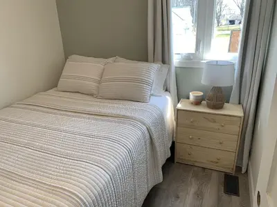 a bedroom with a bed and a nightstand with a window at All Season Cottage close to Long Beach in Wainfleet