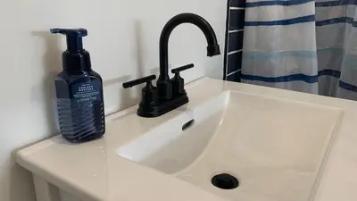 a bathroom sink with a black soap dispenser next to it at All Season Cottage close to Long Beach in Wainfleet
