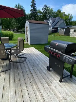 a grill on a deck with a picnic table and a table at All Season Cottage close to Long Beach in Wainfleet