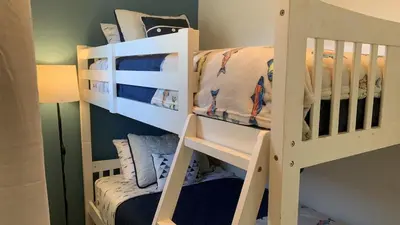 two white bunk beds in a room with a bed at All Season Cottage close to Long Beach in Wainfleet