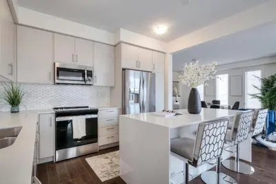 a kitchen with white cabinets and a kitchen island with chairs at Masterfully Designed Private Suite in Bradford