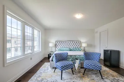 a bedroom with a bed and two chairs and windows at Your Perfect Getaway Master Bedroom in Bradford