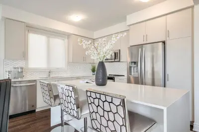a white kitchen with a large white island with chairs at Your Perfect Getaway Master Bedroom in Bradford
