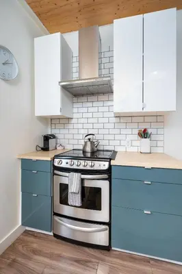 a kitchen with a stove and blue cabinets at Artistic Picton getaway in Picton