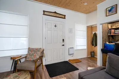 a living room with a door and a chair and a couch at Artistic Picton getaway in Picton