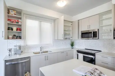 a white kitchen with white cabinets and a window at The Ultimate Staycation in Bradford