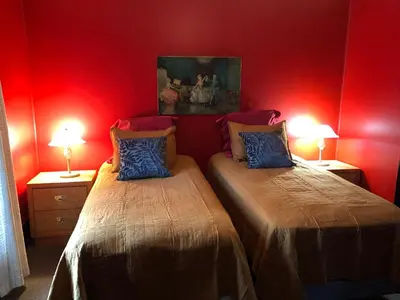 two beds in a room with red walls and two lamps at Lady Hamilton in Stratford